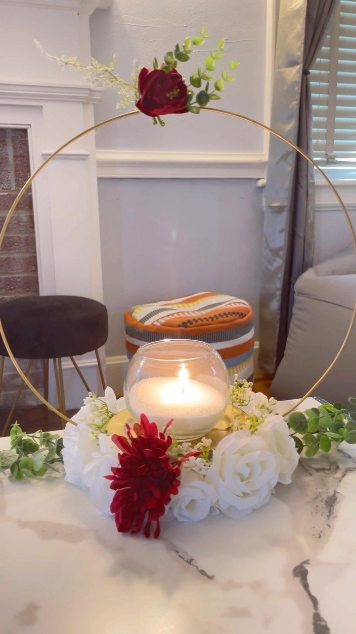 Lit candle in a glass bowl surrounded by white and red roses with gold hoop.