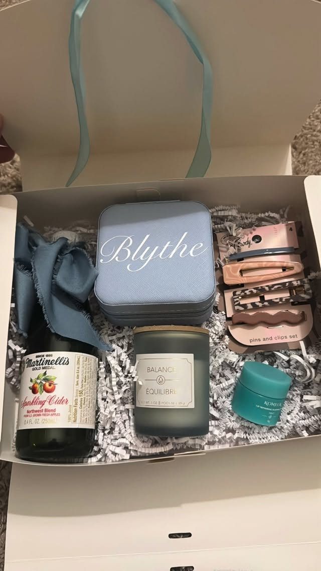 Gift box with sparkling cider, personalized blue box, candle, and beauty accessories.