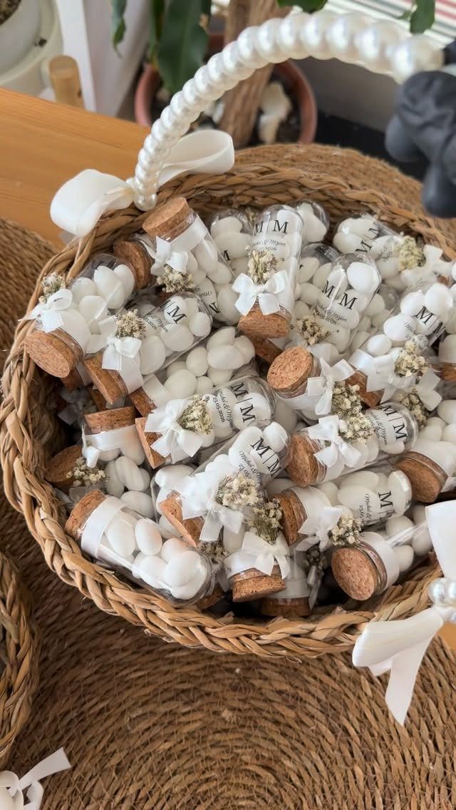 Small glass vials with white candies and dried flowers in a wicker basket.