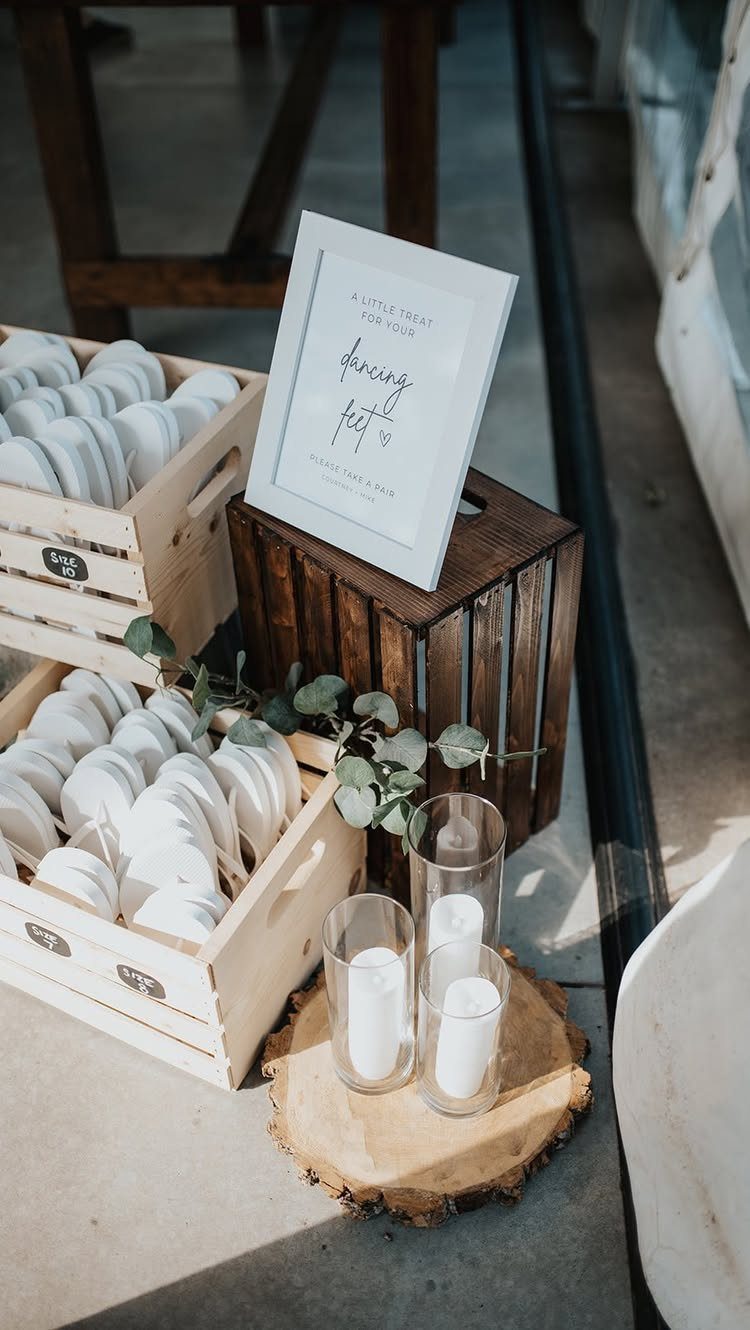 White flip flops in wooden crates with a dancing feet sign and candles.