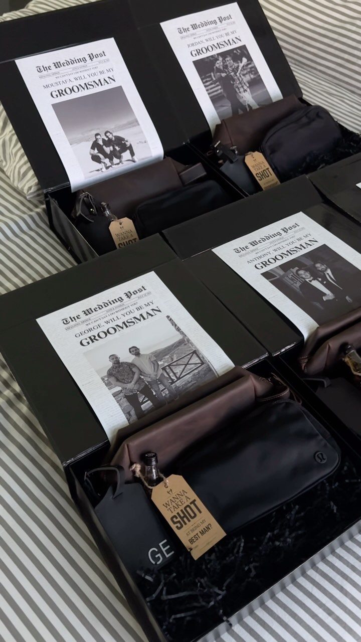 Black groomsmen gift boxes containing brown toiletry bags and personalized groomsman cards.