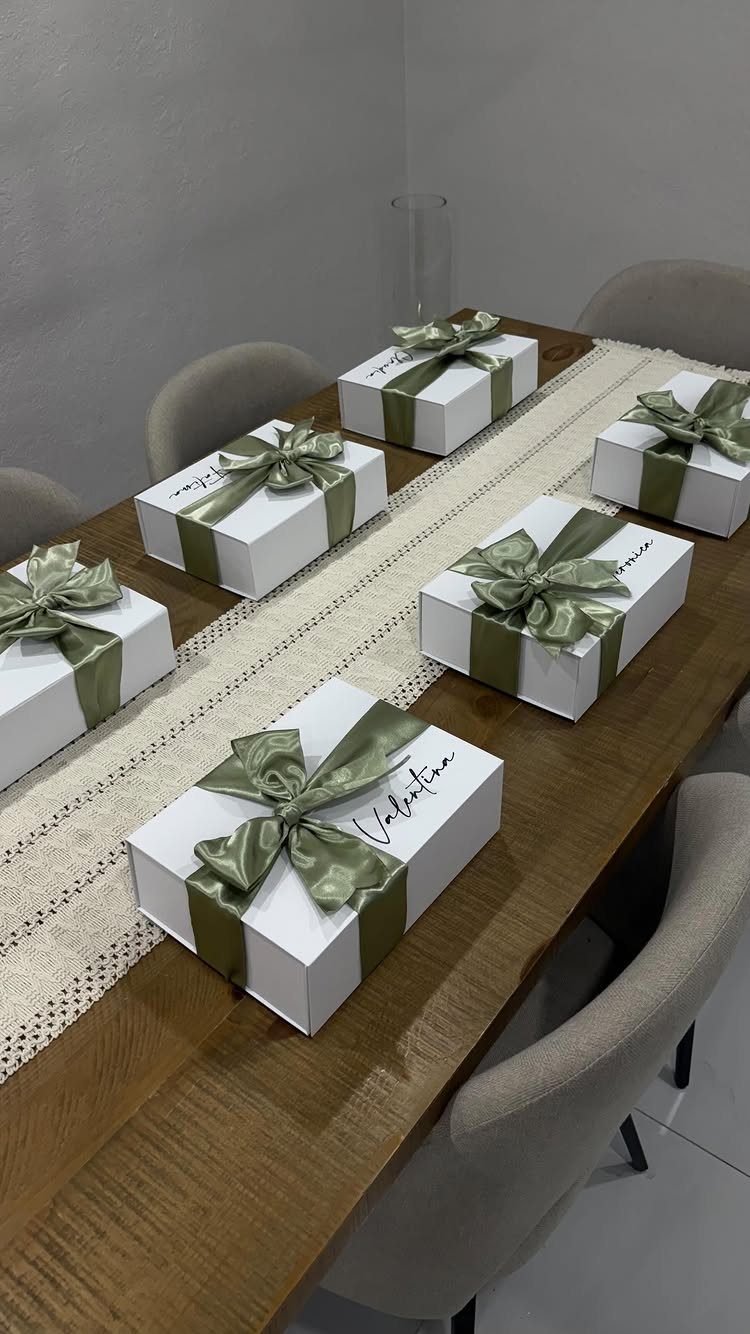White gift boxes with olive green ribbons on a lace table runner.