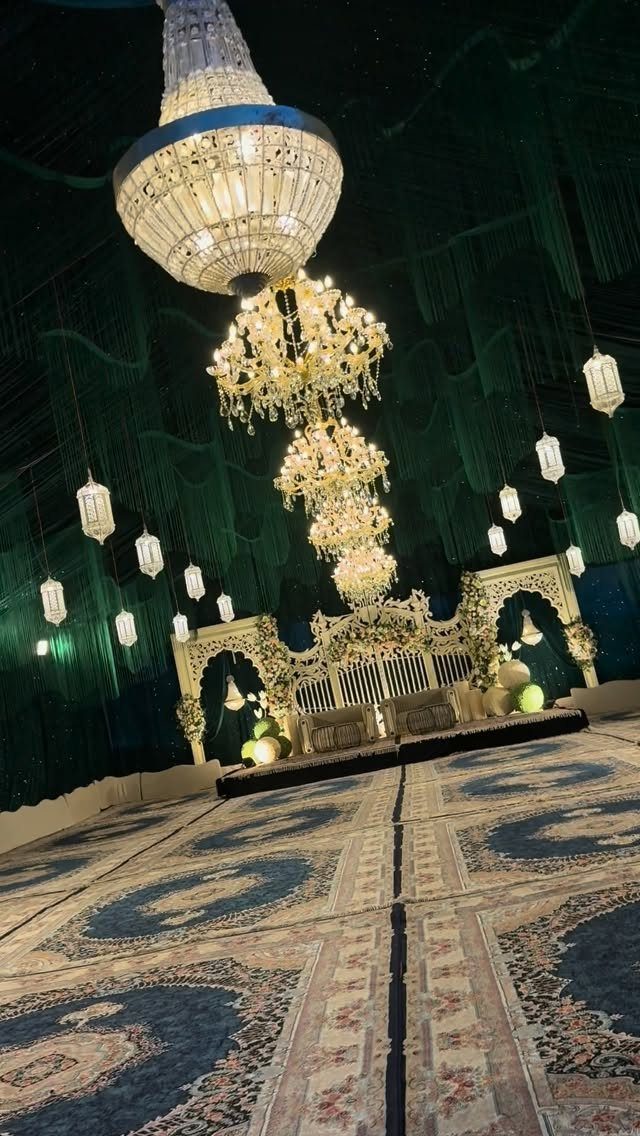 Emerald green fabric draping a room with crystal chandeliers and ornate white stage.
