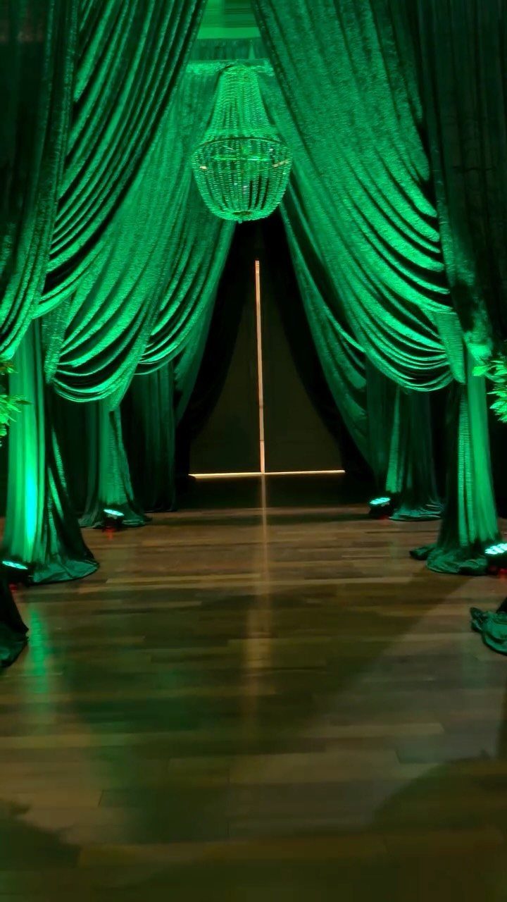 Emerald green draped curtains and a crystal chandelier framing a wedding entrance hallway