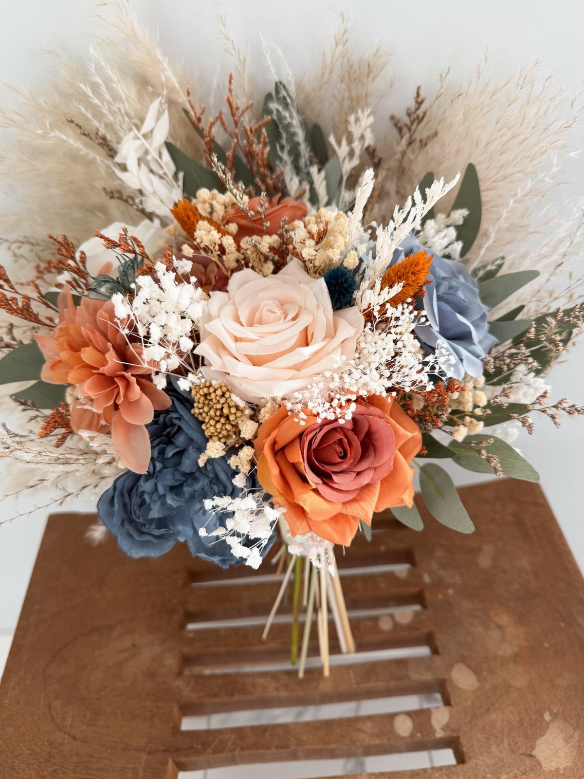 Bridal bouquet with rust orange and dusty blue roses and dried pampas grass.