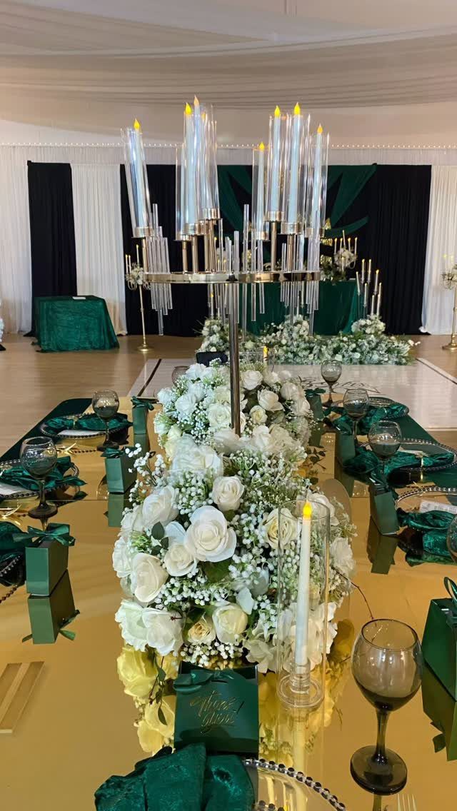 Wedding table setting with emerald green napkins and white rose floral centerpieces.