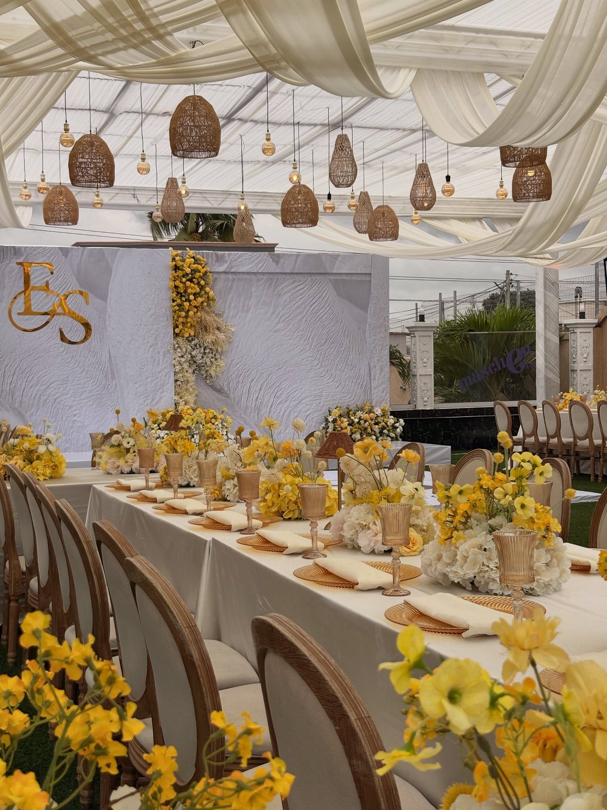 Wedding table setting with ivory linens, gold accents, and yellow floral centerpieces.