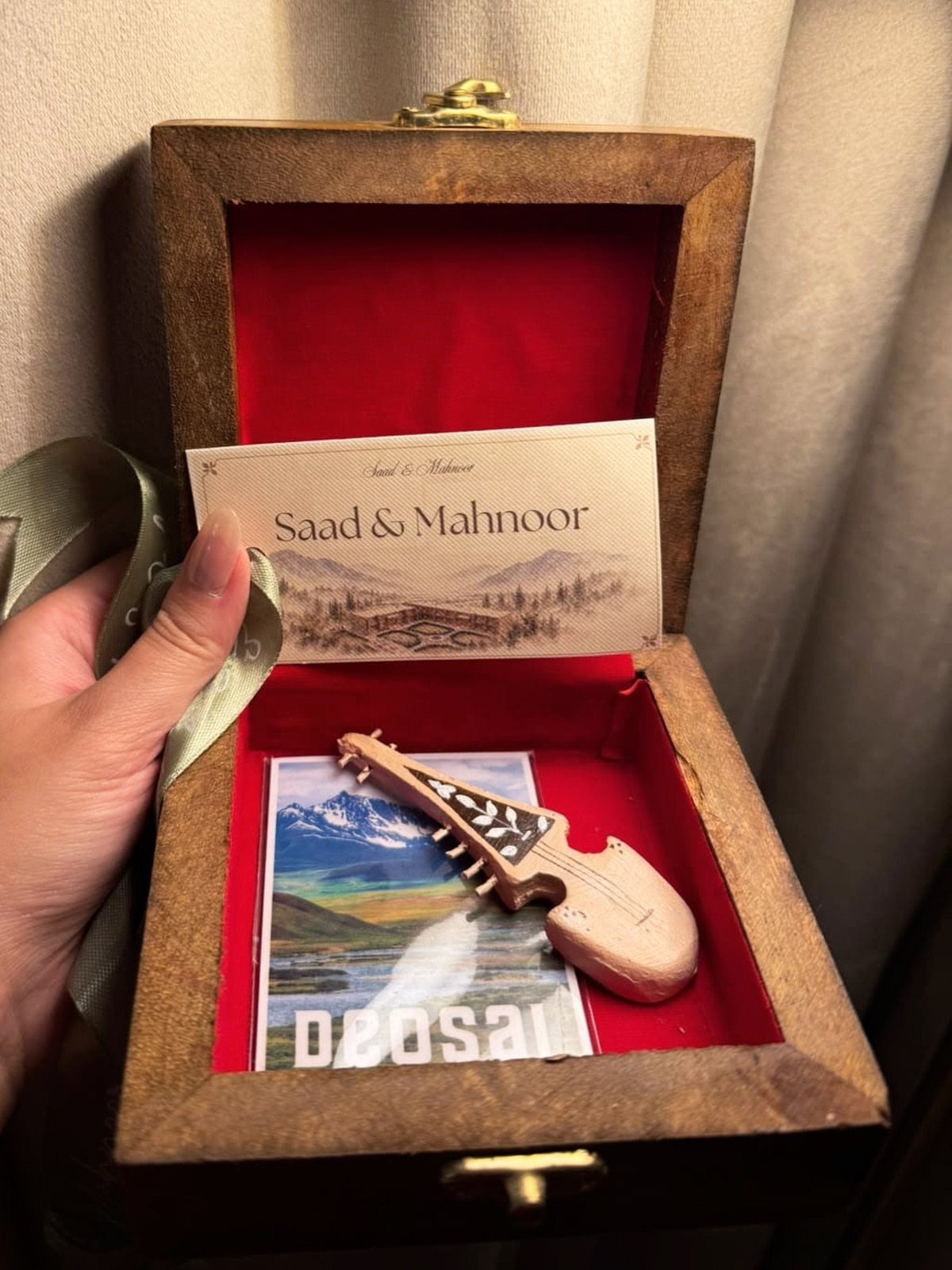 Wooden gift box with red lining containing a small instrument and personalized card.