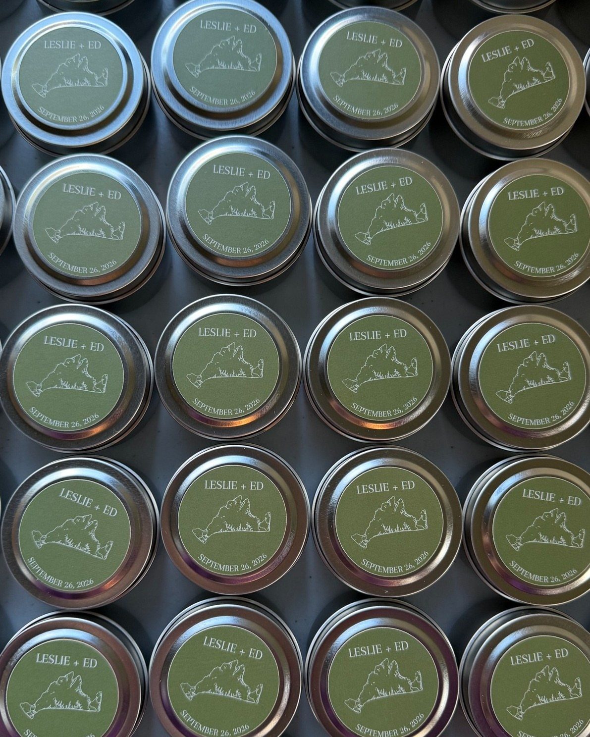 Small silver metal tins with olive green labels and white geographic outlines.