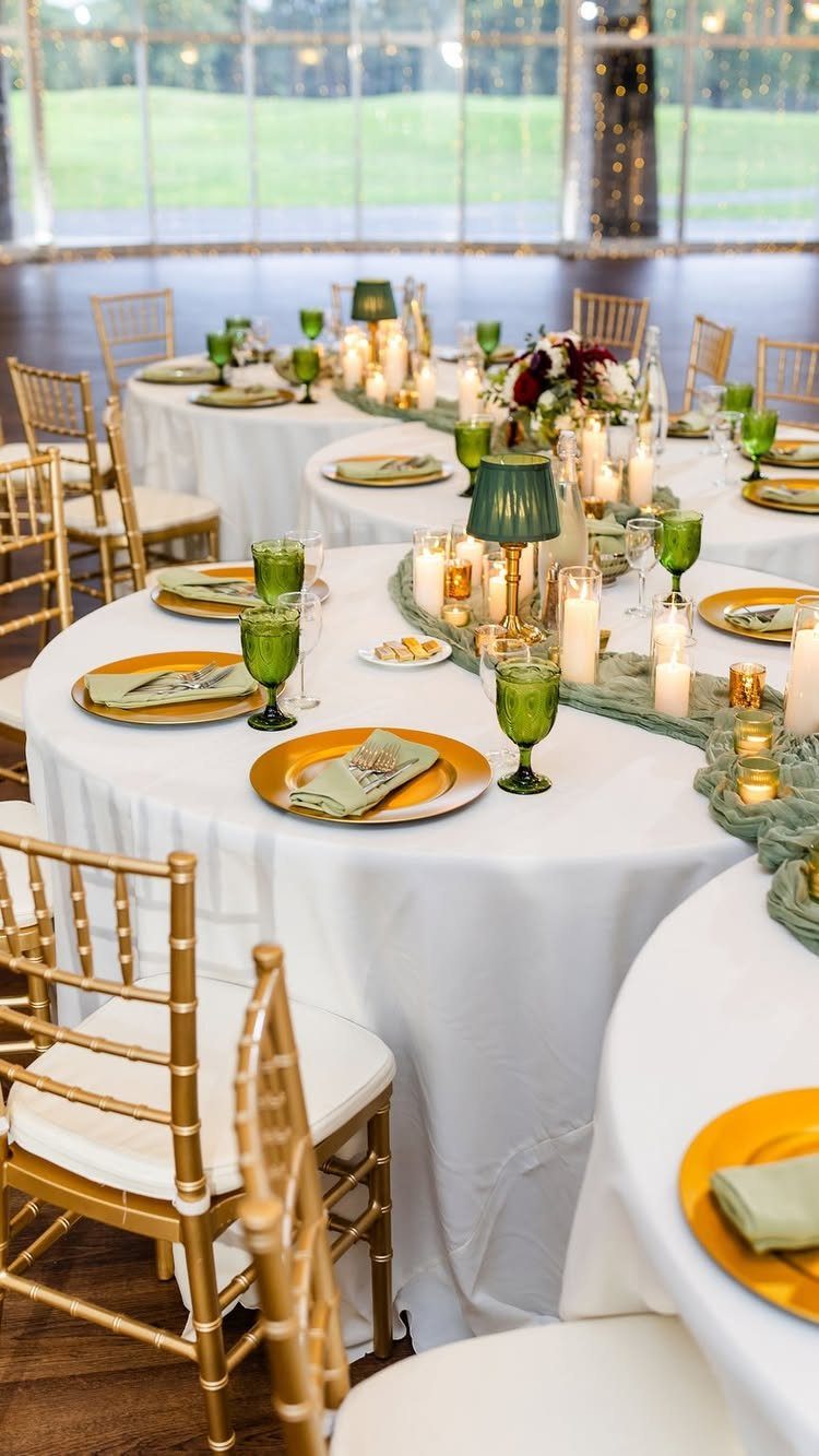 Round wedding tables with white linens, gold chairs, and floral centerpieces with candles.