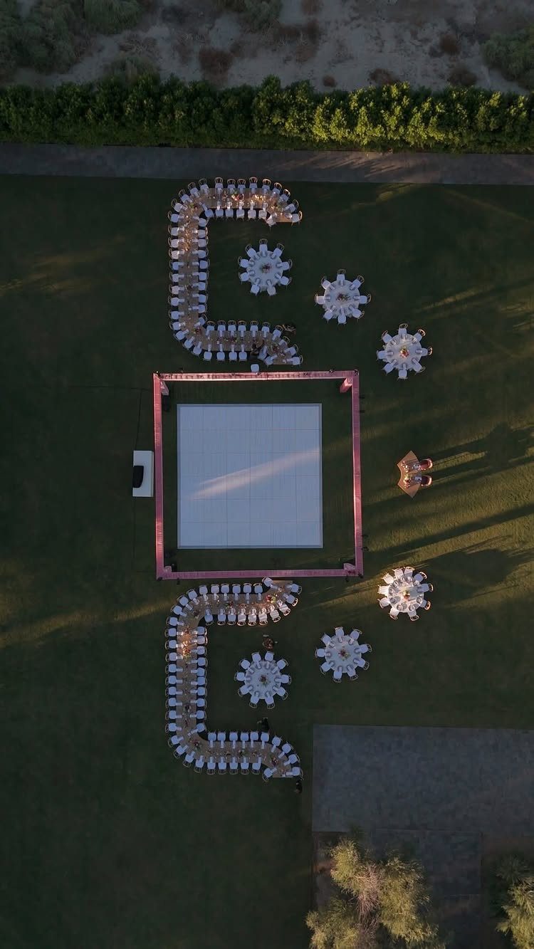 Aerial view of outdoor wedding layout with dance floor and white seating arrangements.
