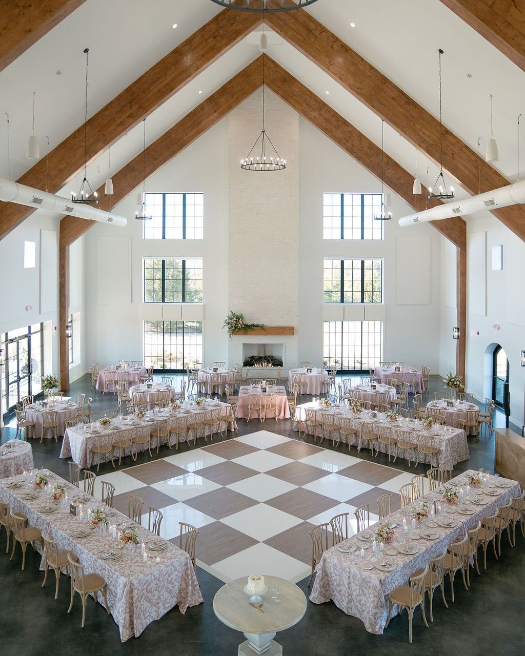 Wedding reception hall with symmetrical table arrangements surrounding a checkered dance floor.
