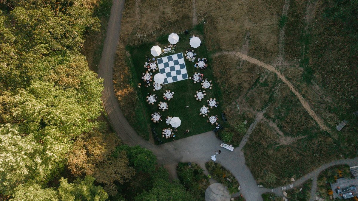 Aerial view of outdoor wedding layout with checkered dance floor and dining tables.