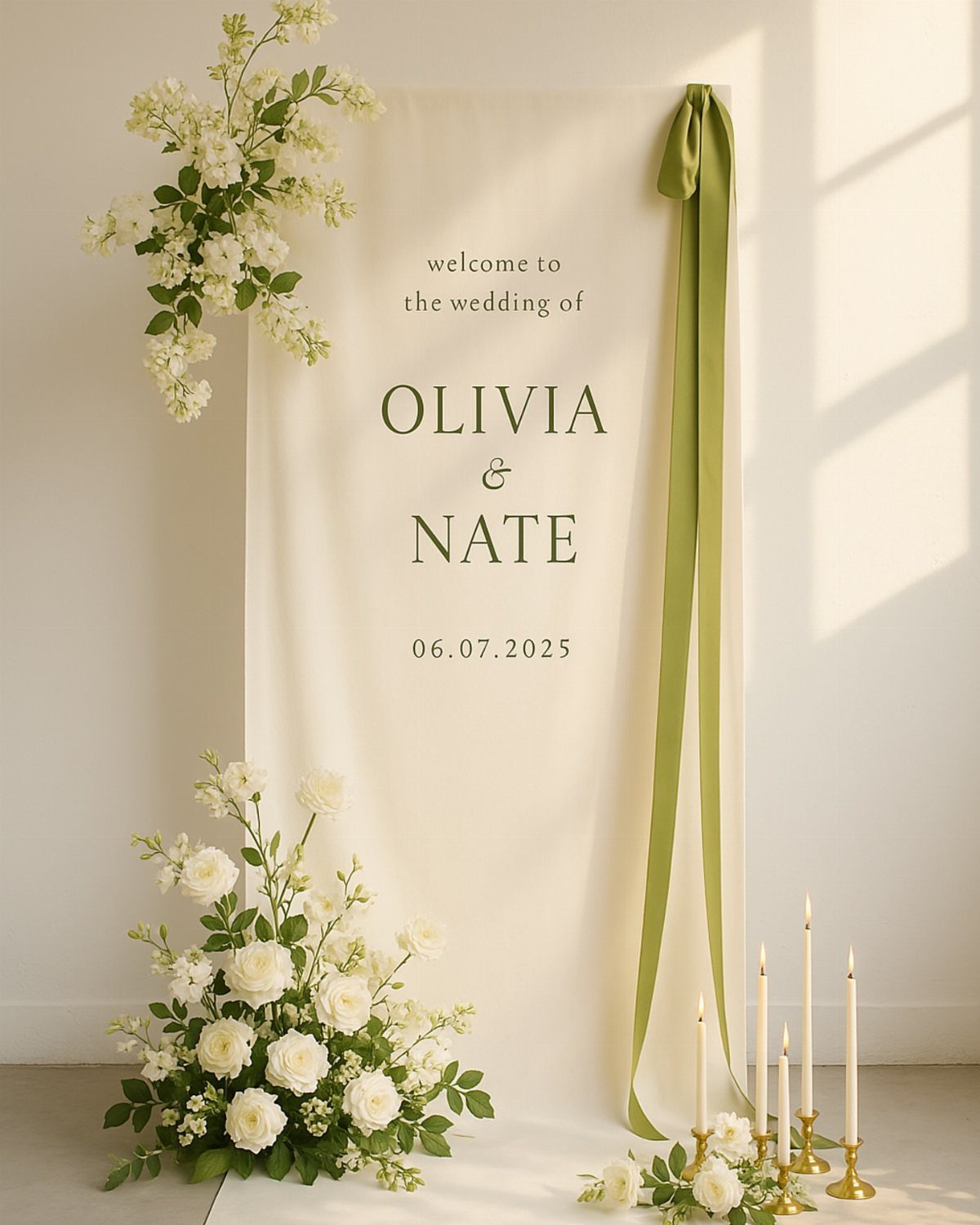 White fabric wedding backdrop with olive green ribbon and white floral arrangements.