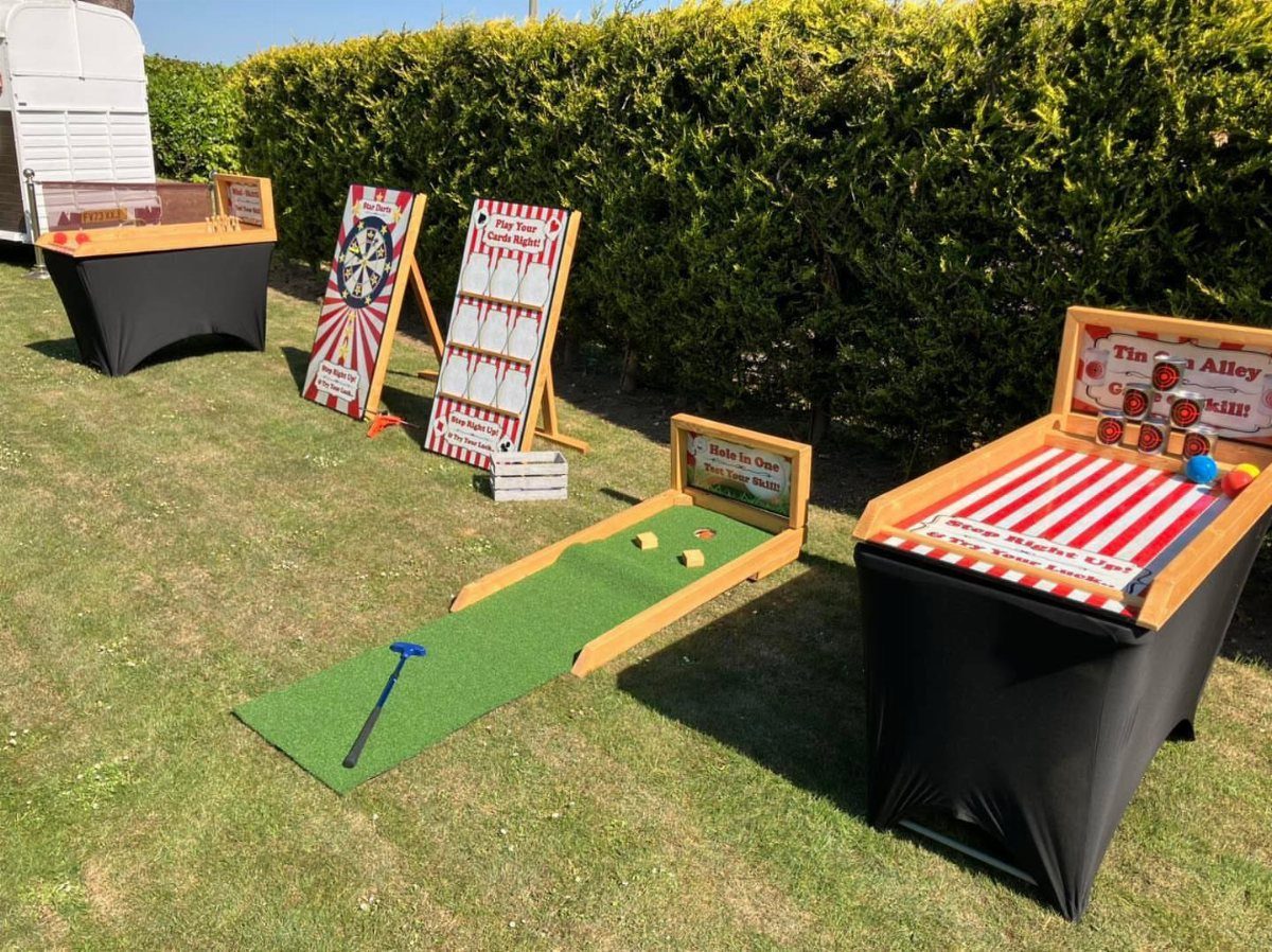Carnival yard games set up on a green lawn against a hedge background.