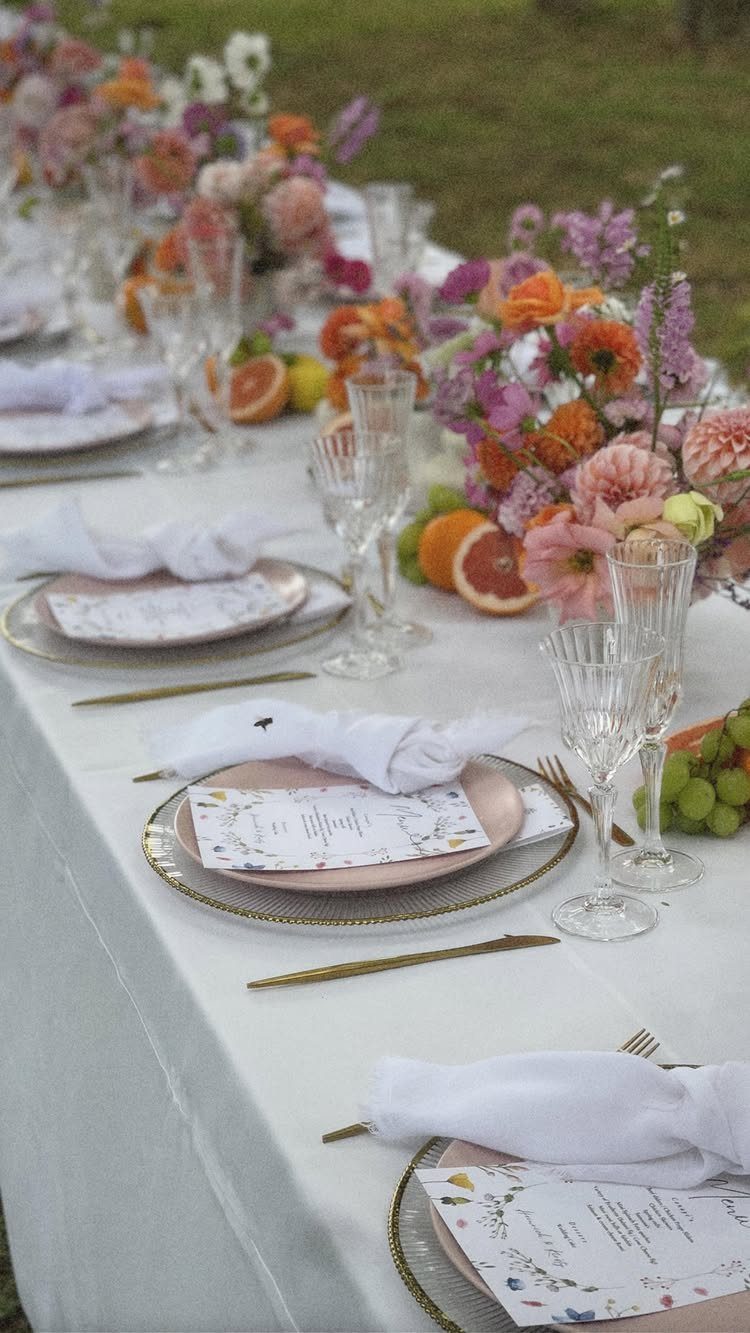 Table runner with colorful flowers and sliced citrus fruits on a white tablecloth.