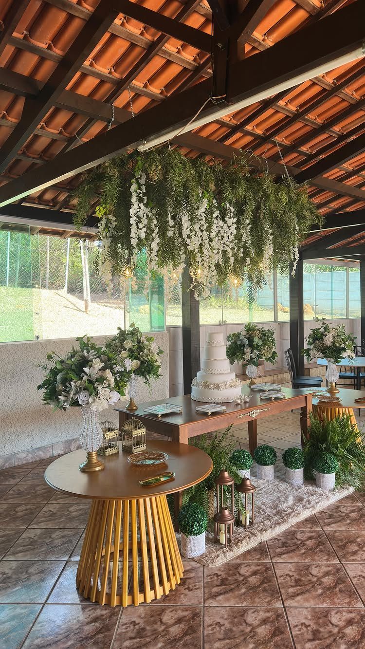 Hanging greenery and white flowers suspended from a wooden ceiling over a wedding table.