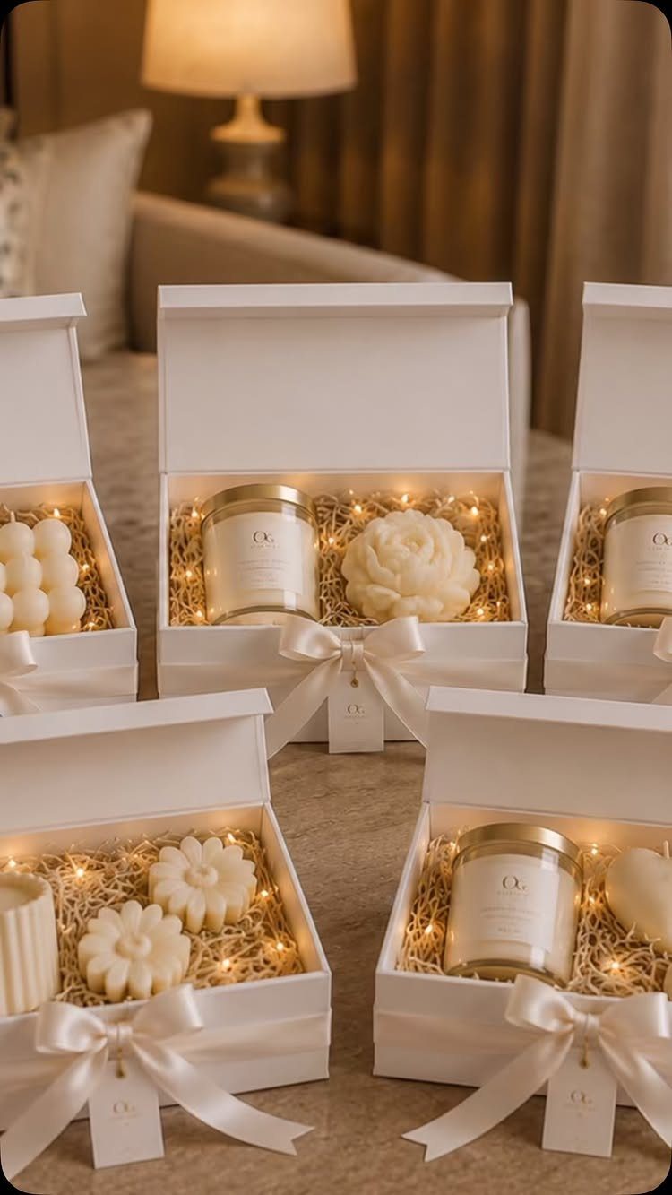 White gift boxes containing candles and fairy lights tied with satin ribbons