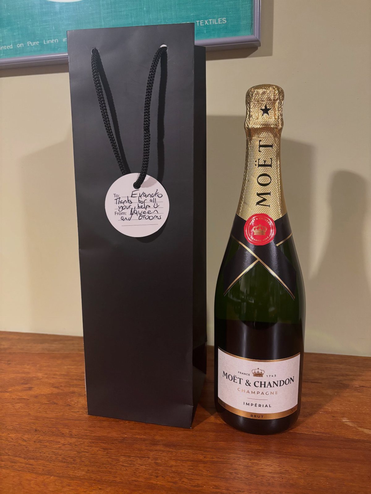 Moët & Chandon champagne bottle next to a black gift bag with a tag.