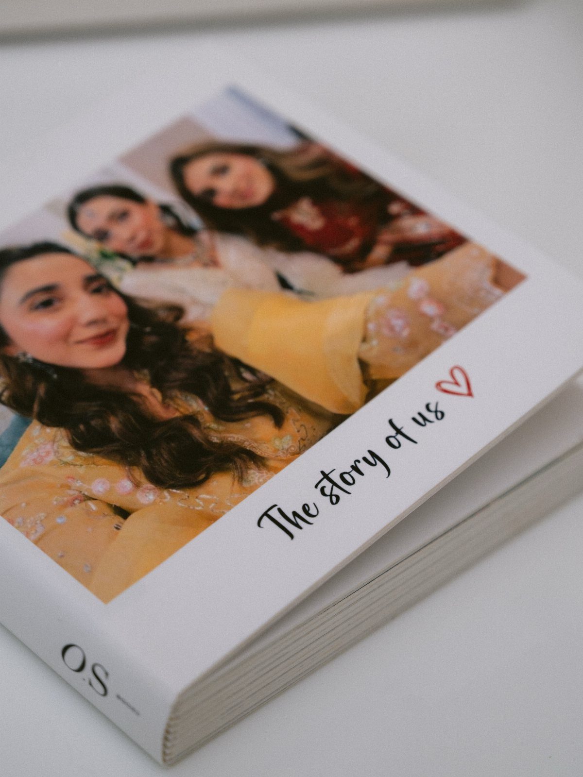 White hardcover photo album with a picture of women and cursive text.