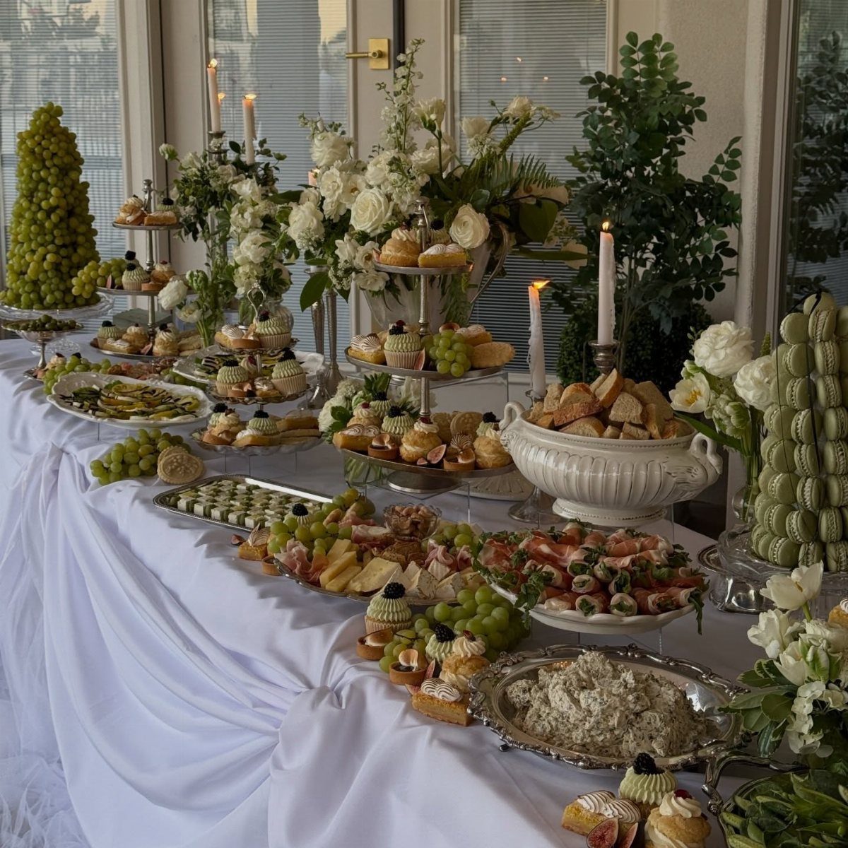 Buffet table with appetizers, green grapes, and white flowers for a wedding reception.