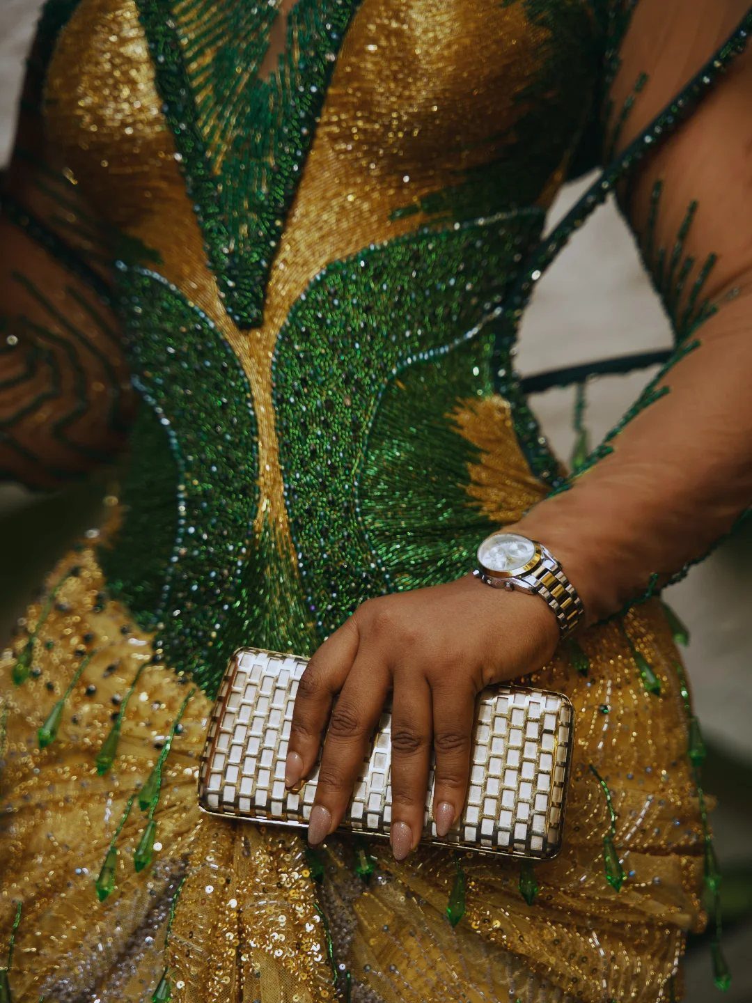 Emerald green and gold beaded dress with a matching white and gold clutch.