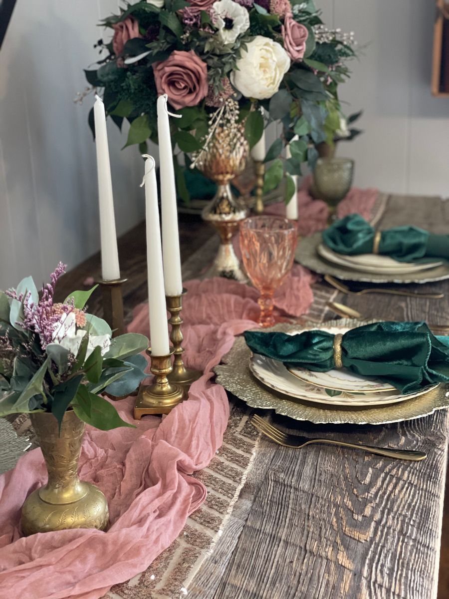 Gold chargers and cutlery on a wooden table with pink runner and florals