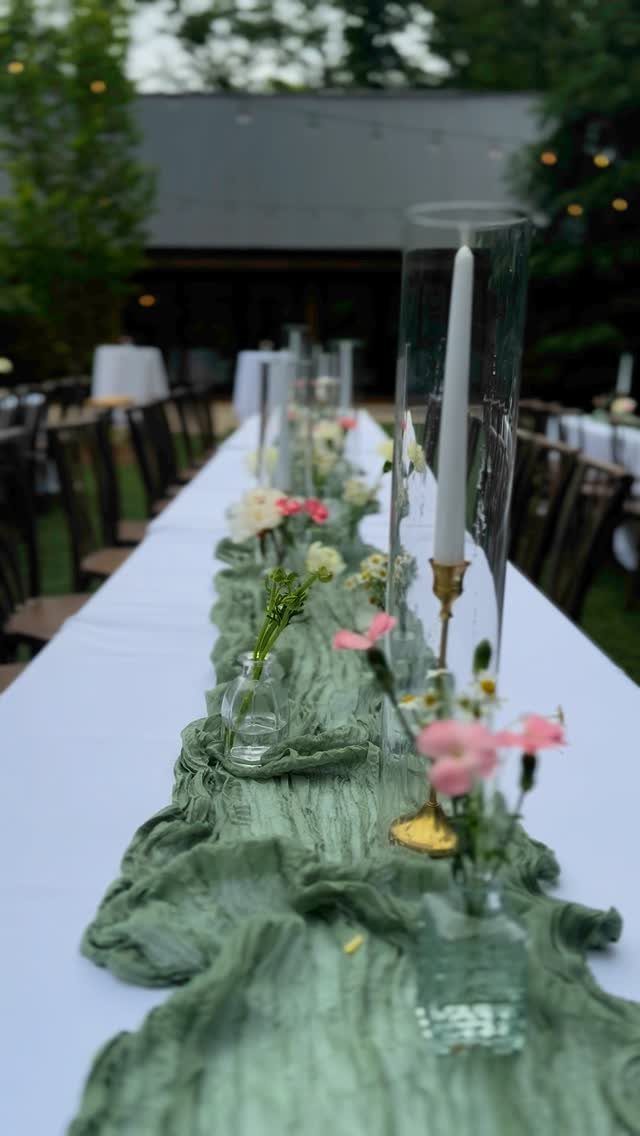 Sage green gauzy table runner with pink flowers and white candles on white table