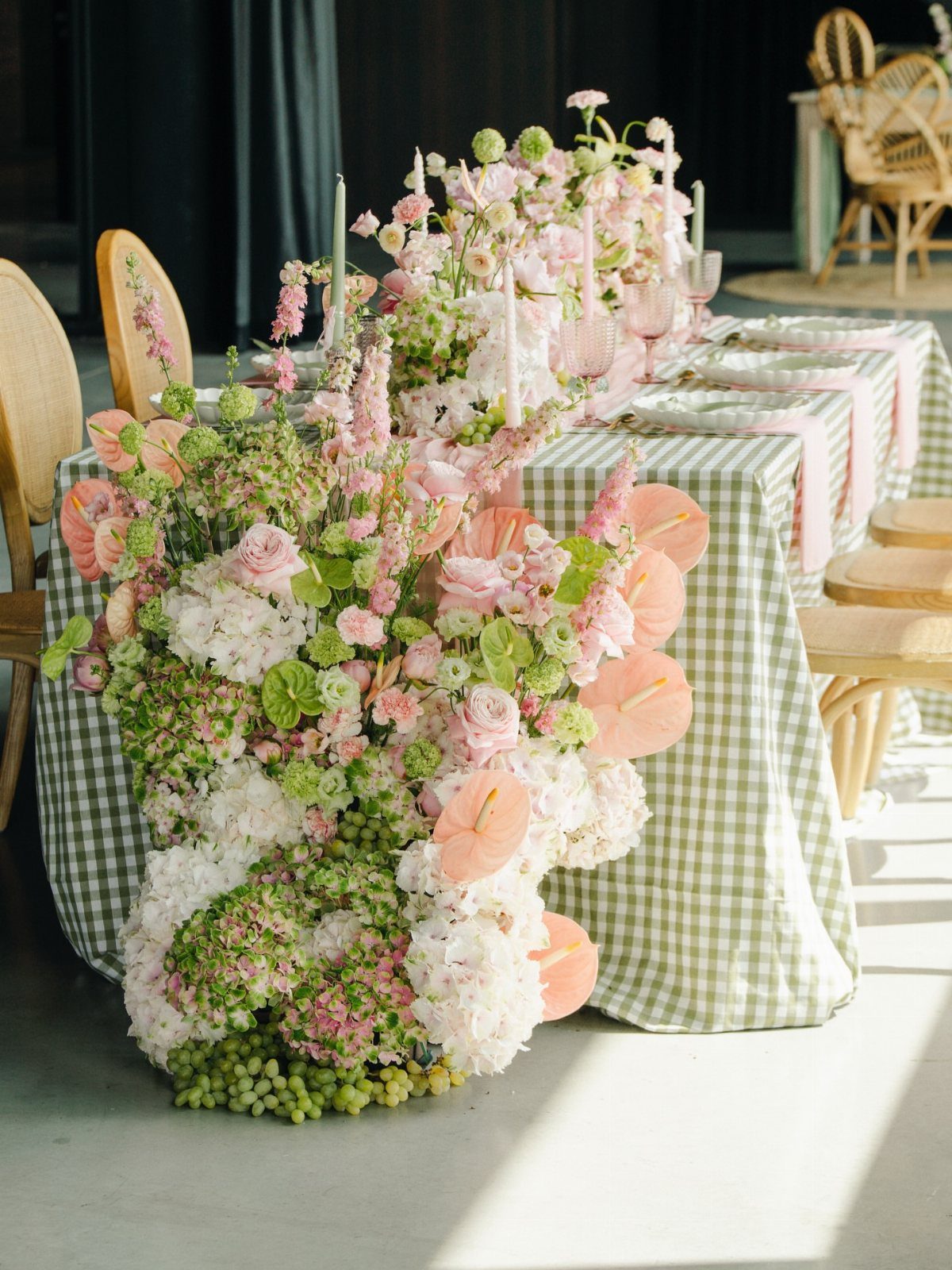 Green and white gingham table with cascading pink and white floral arrangements.