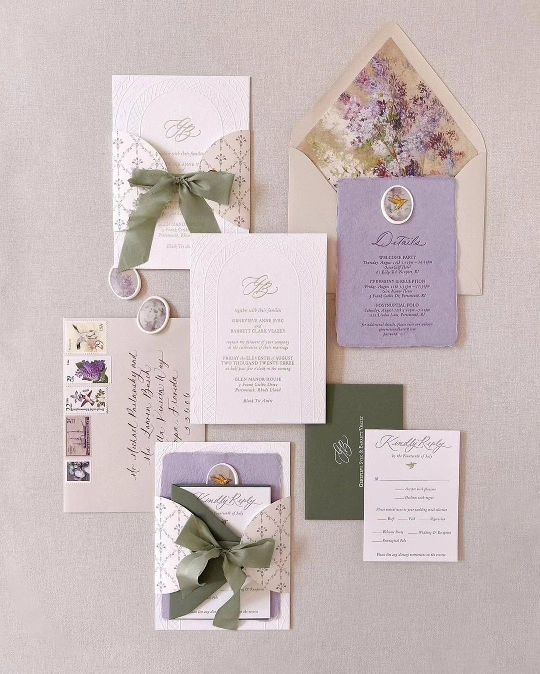 Wedding invitation suite with sage green ribbons and lavender envelopes on neutral fabric.
