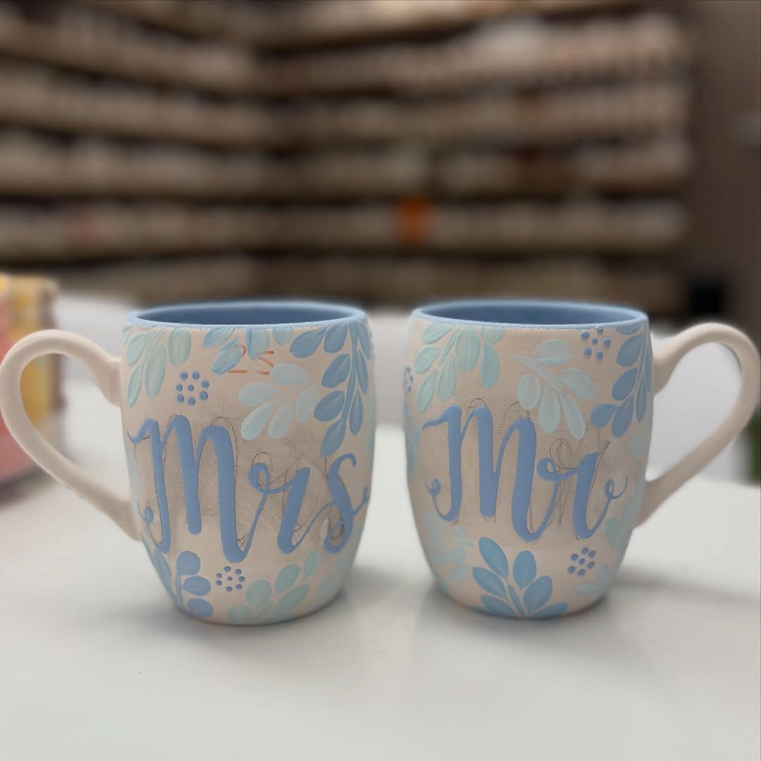 Two cream ceramic mugs with blue floral designs and Mr and Mrs lettering.