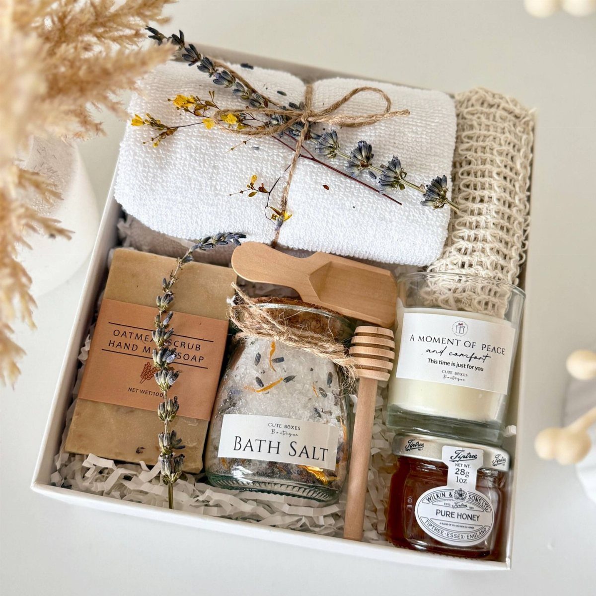 Spa gift basket with bath salts, candle, honey, soap, and a white towel.
