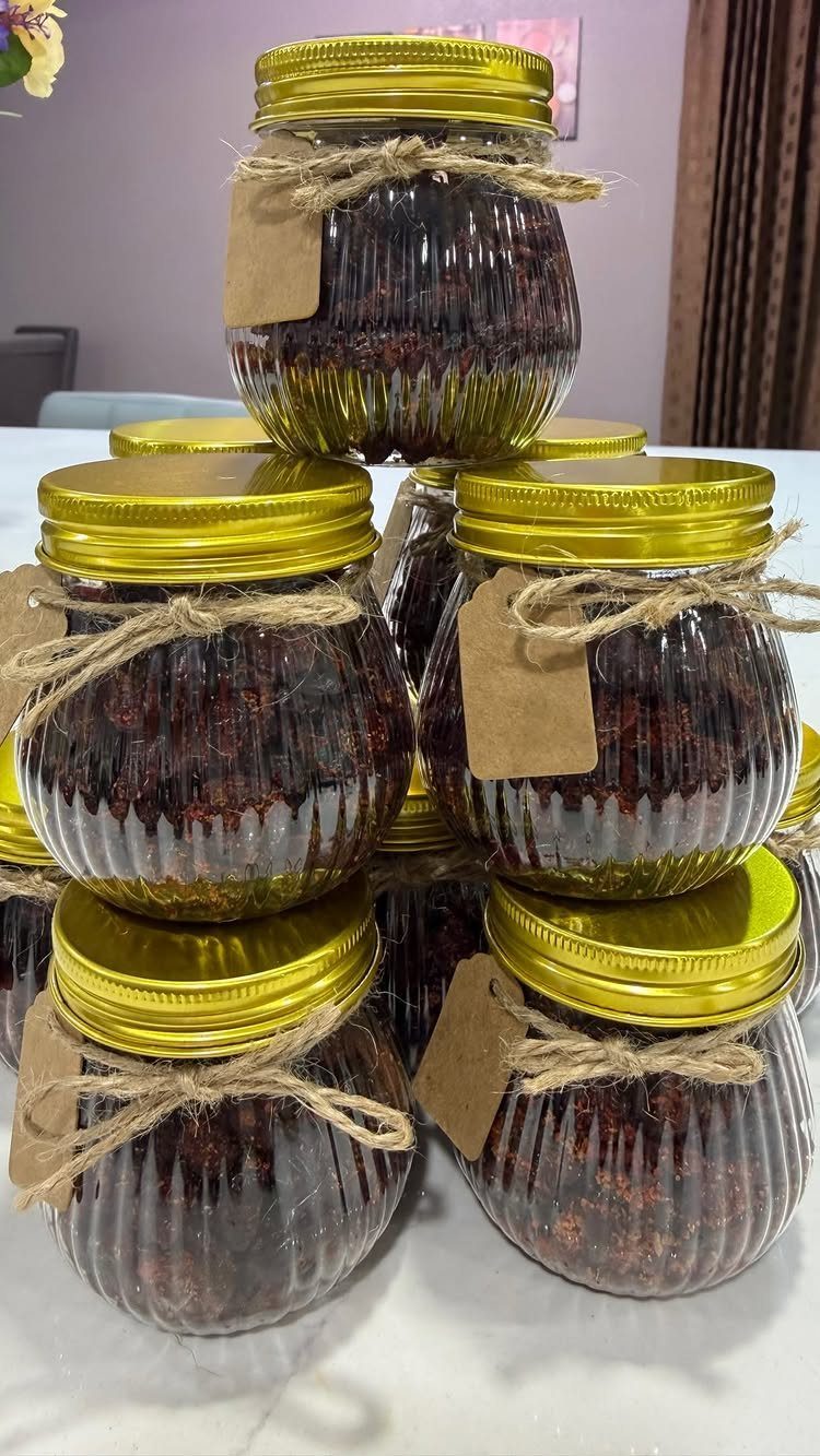 Ribbed glass jars filled with red jam, tied with twine and gift tags.
