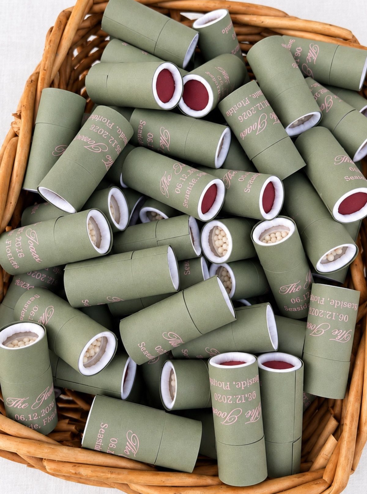 Olive green cardboard seed tubes with pink text inside a wicker basket