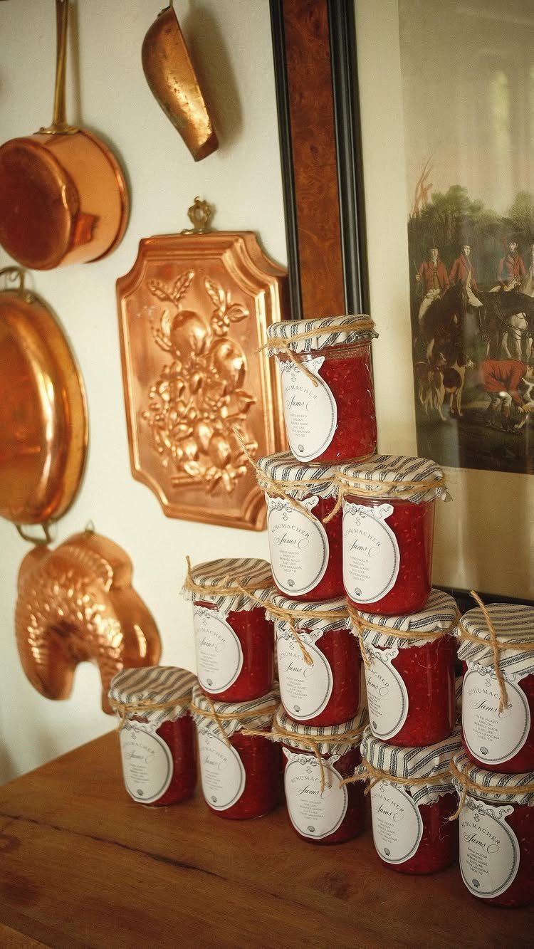 Small jars of red jam with fabric lids and twine on wooden table