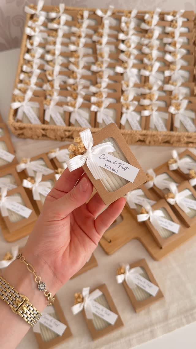 Hand holding a small brown gift box with white soap and ribbon favors