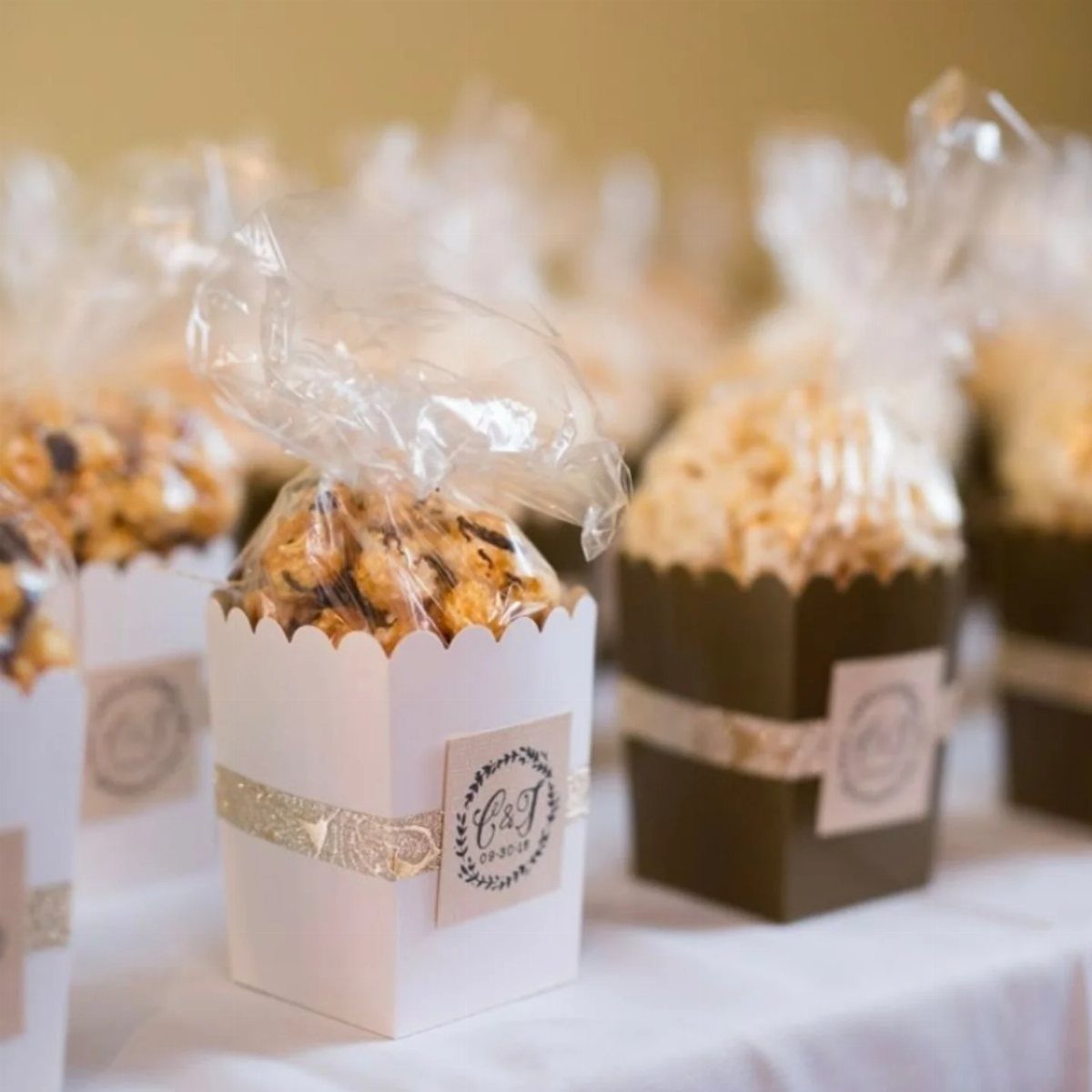 Popcorn snacks in white and brown cardboard boxes with personalized labels and ribbons.