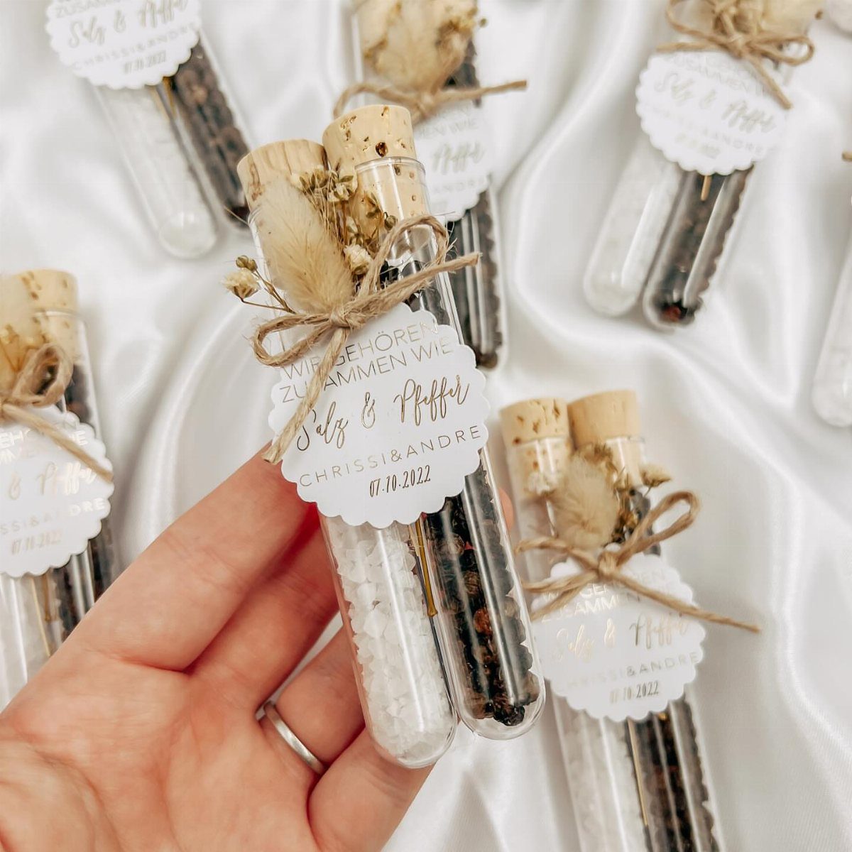 Two small glass tubes of salt and pepper tied with twine and tags.
