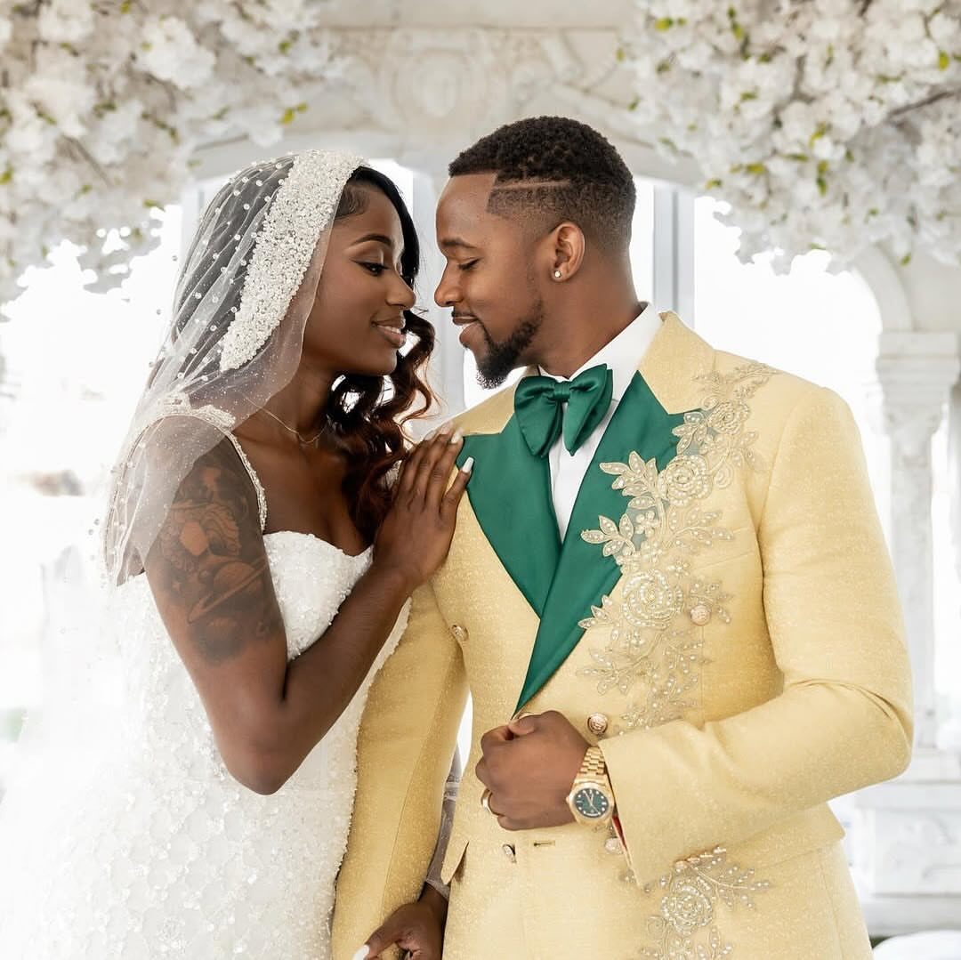 Bride and groom posing, groom wearing a gold suit and emerald green bow tie.
