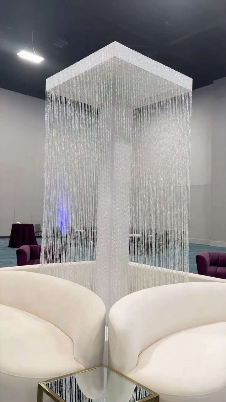 White curved sofas and silver beaded curtains with purple velvet accents in a lounge.