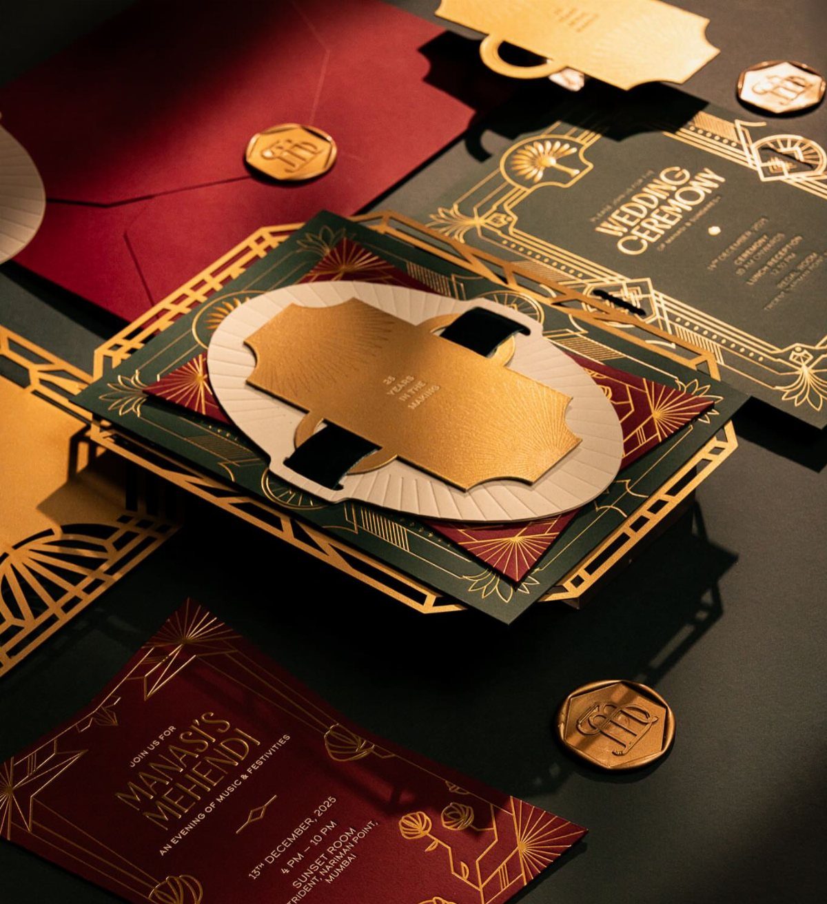Luxury wedding invitations with emerald green and burgundy colors and gold foil accents.
