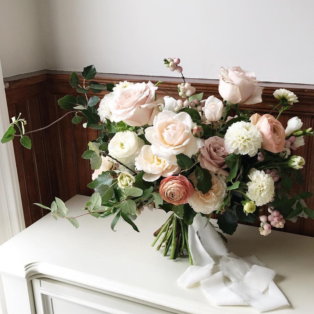 Blush and cream rose bridal bouquet resting on a white vintage dresser.