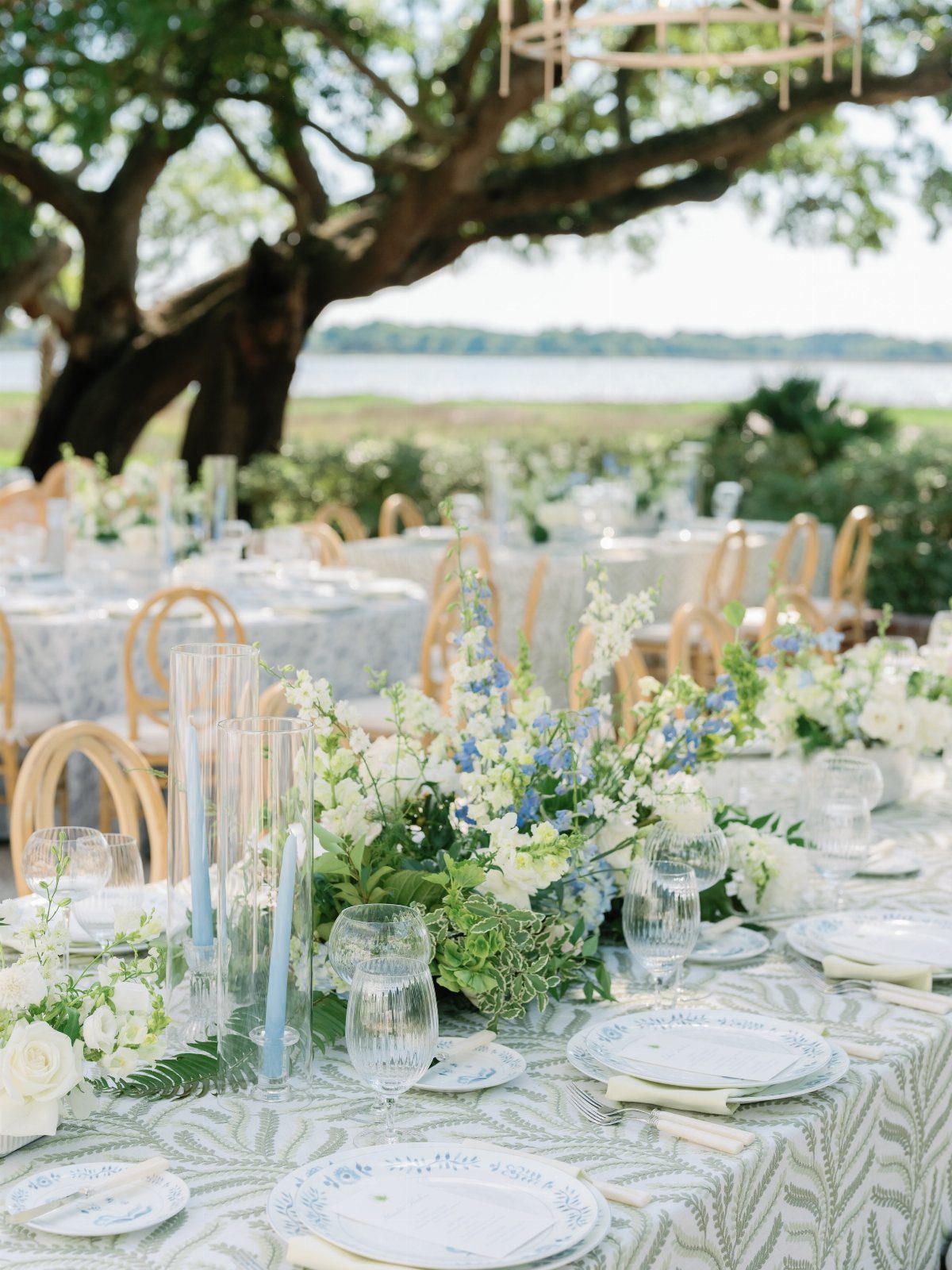 Outdoor wedding table with light blue and white linens and coastal floral centerpieces.