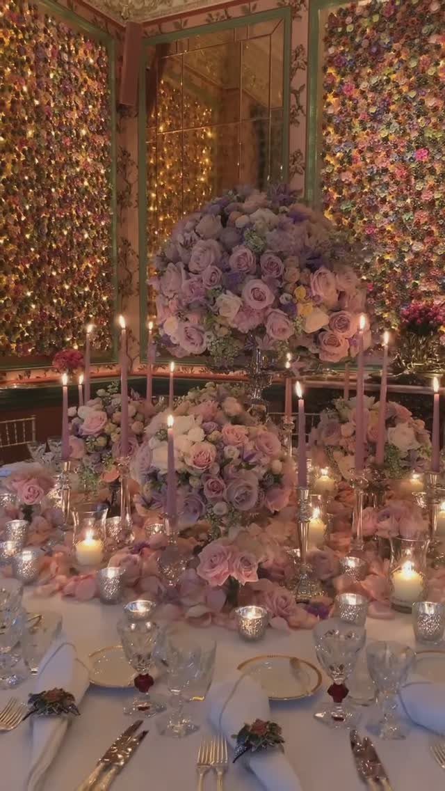 Lilac and pale pink floral centerpieces with gold plates on a white table.