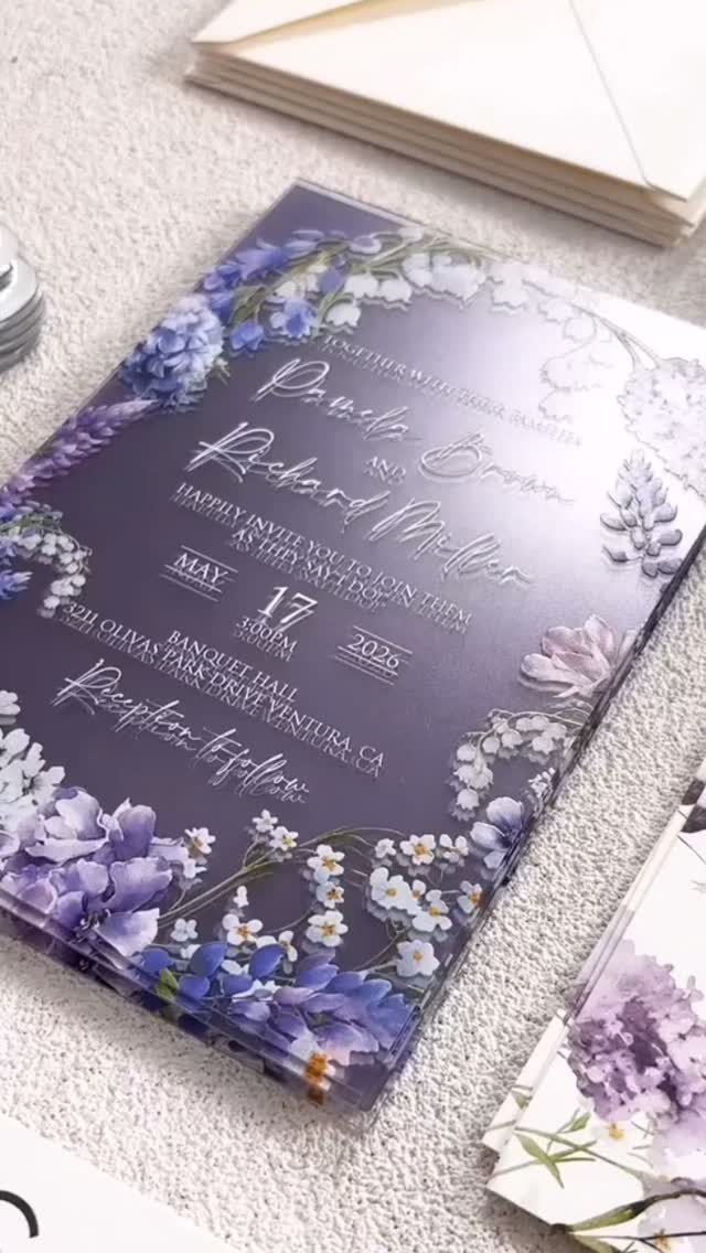 Translucent purple acrylic wedding invitation with lilac floral borders and white cursive text.
