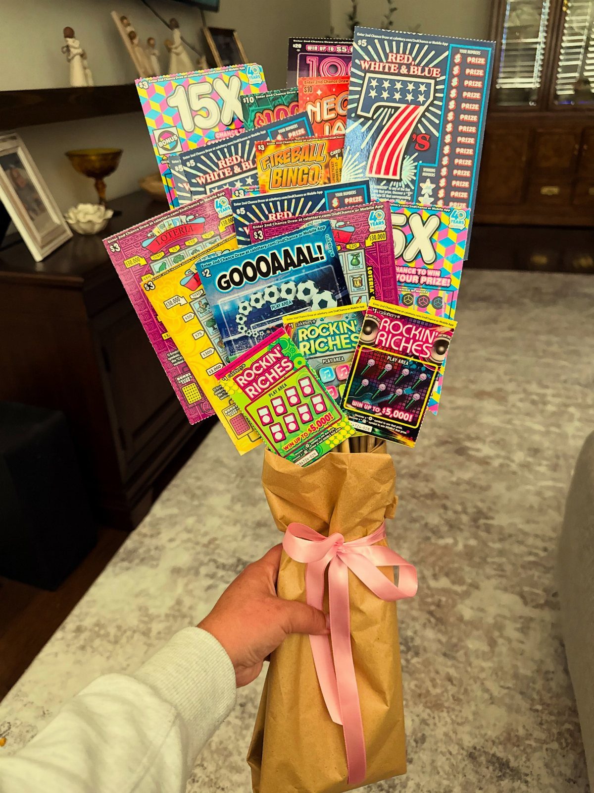 Lottery ticket bouquet wrapped in brown paper with a pink ribbon bow.