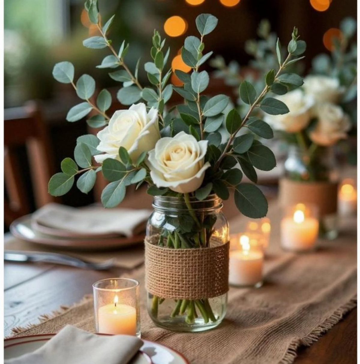 Mason jar with white roses and eucalyptus wrapped in burlap on a table