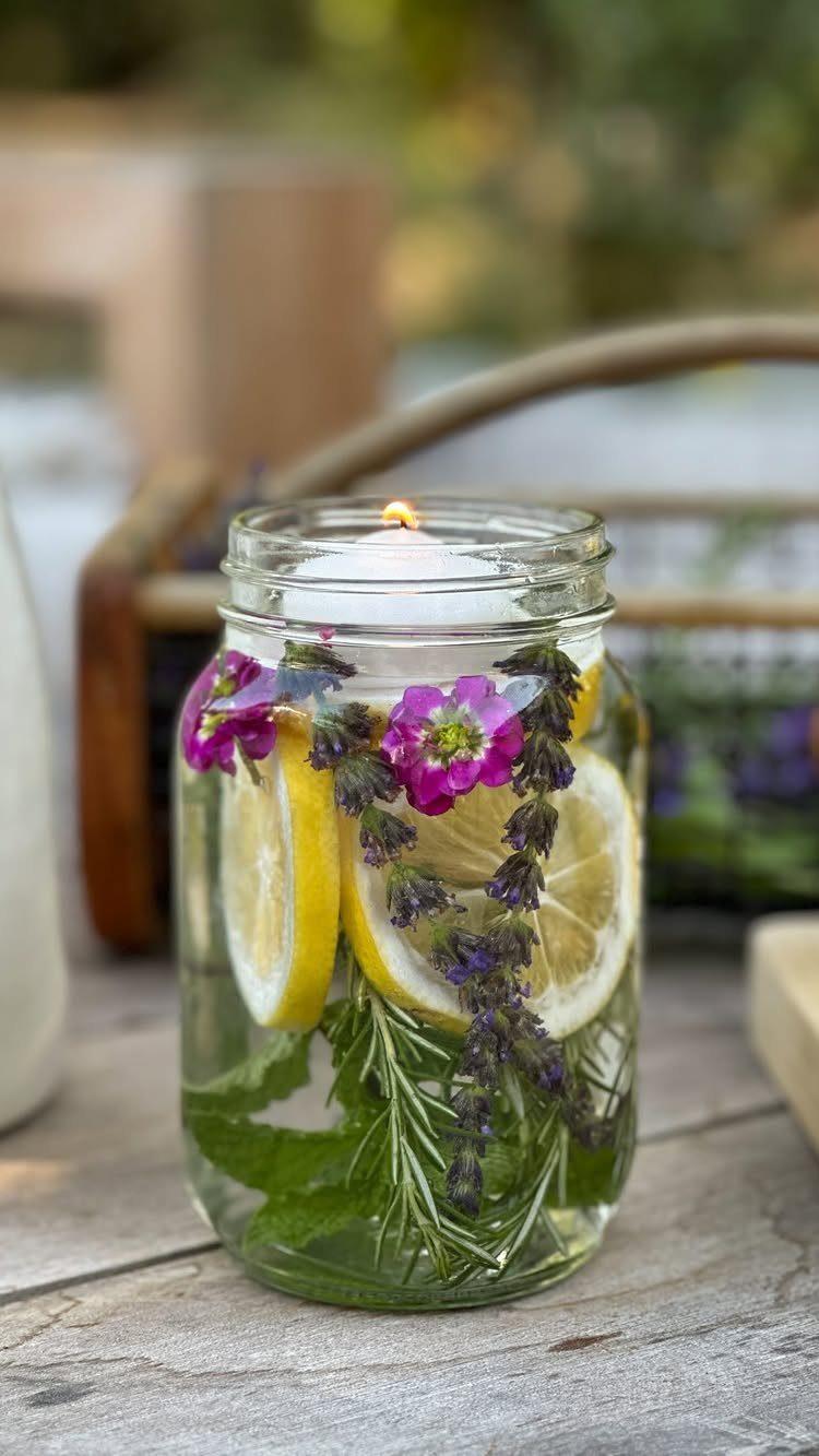 Floating white candle in a mason jar with lemon slices and purple flowers