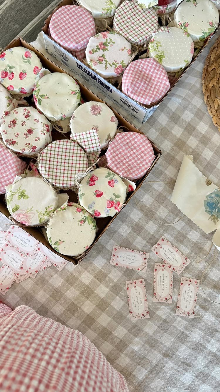 Mason jars with fabric lids and gift tags arranged on a checkered tablecloth.