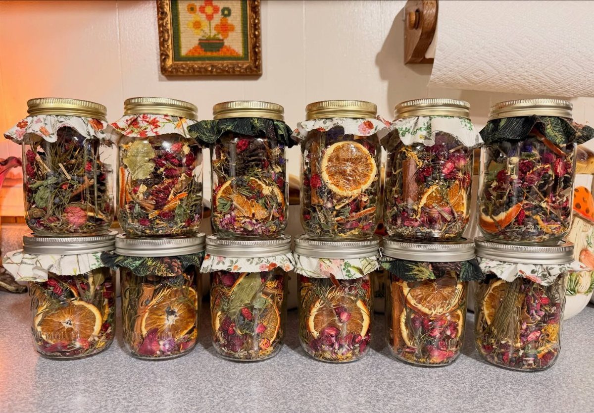 Mason jars filled with dried botanicals and orange slices with decorative fabric lids